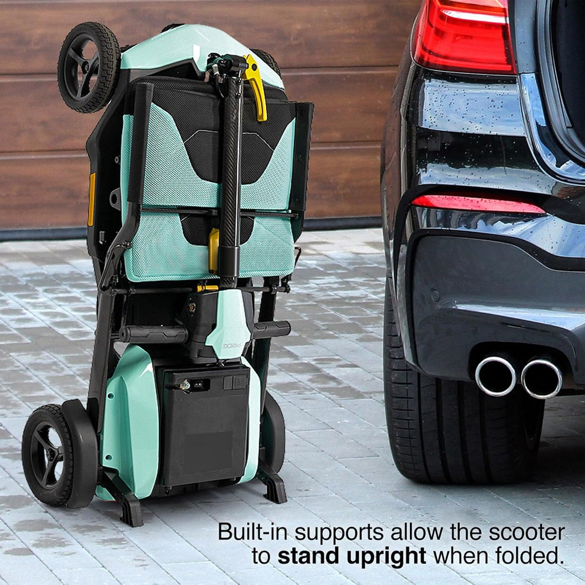 Pride Mobility Go-Go Super Portable Scooter folded upright next to a car, showcasing its convenient design.