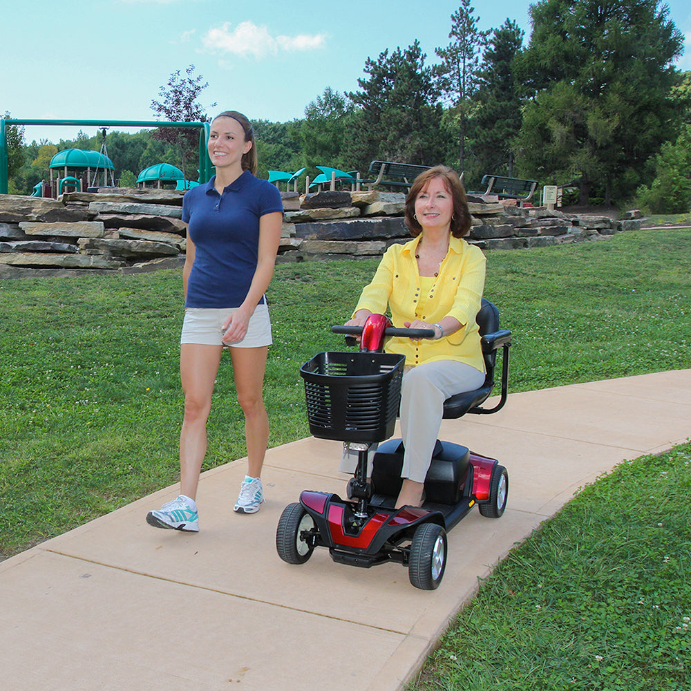 Woman enjoying the outdoors on a Go-Go Sport scooter rental with a companion walking beside her.
